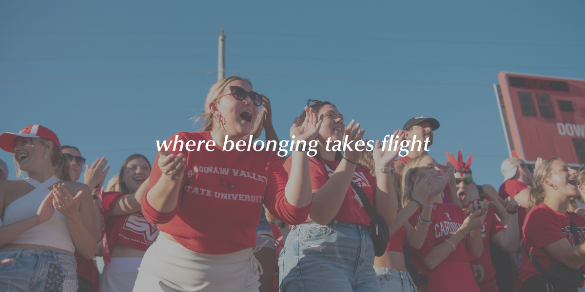 Students cheering in the student section of an SVSU football game with text overlaying the image that says